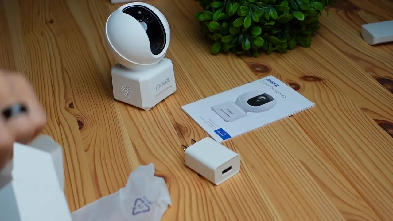 Annke Creator Pro camera, power adapter, and quick start guide on a wooden table