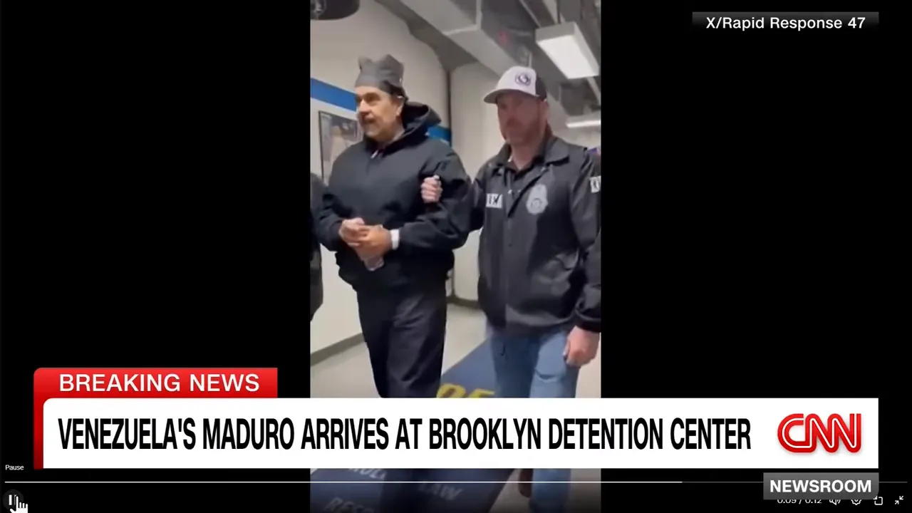 Close-up of a handcuffed person escorted by an agent holding his arm in a corridor with CNN 'Breaking News' banner