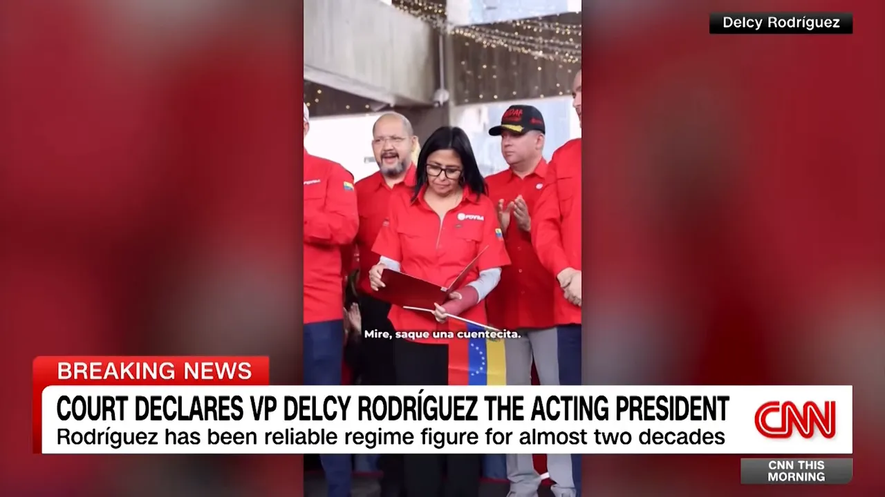 Delcy Rodríguez surrounded by party officials in red shirts, looking at a folder with a small Venezuelan flag visible.