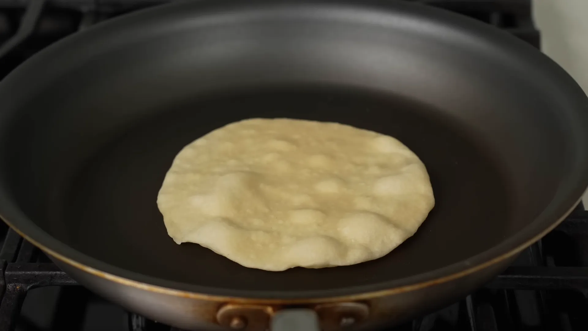 Fresh tortilla puffing on a pan and developing bubbles
