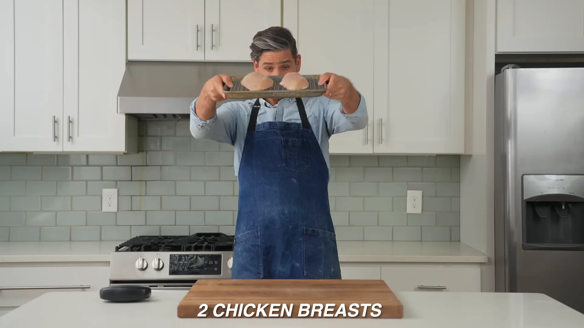 Two chicken breasts on cutting board being prepped