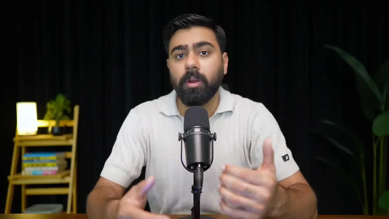 Presenter at a desk speaking into a microphone, gesturing with hands while describing automation features.