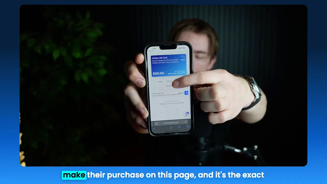 Phone held to camera showing a mobile gift card checkout page with a $50 selection visible
