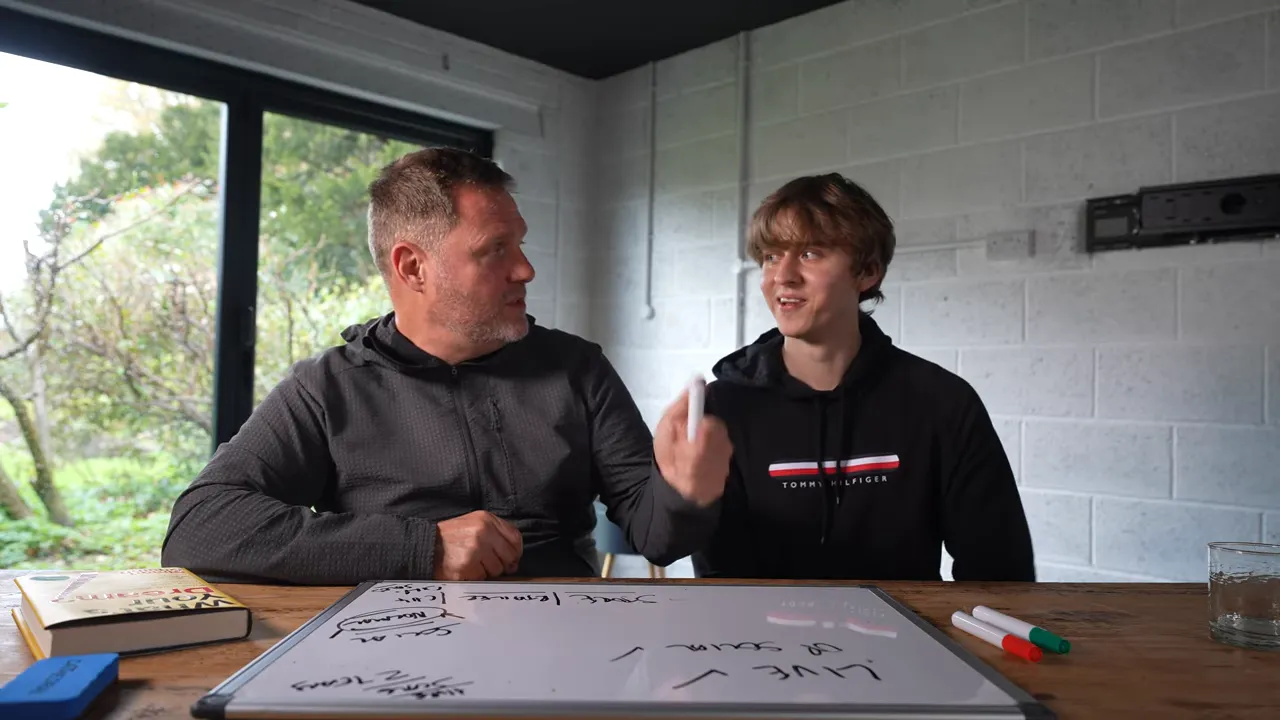 Two founders at a table mapping a funnel on a whiteboard; one holds a marker while they discuss planning and next steps.