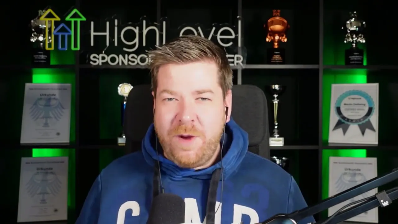 Presenter Martin facing camera in front of HighLevel-branded shelving and trophies, speaking into a microphone with a confident expression.
