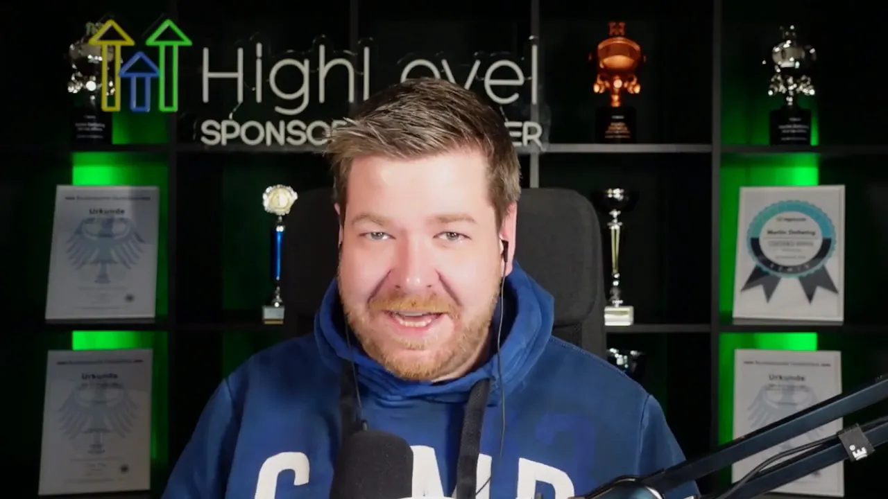 Host facing camera in front of a HighLevel sponsor backdrop with awards and a microphone, speaking about platform consolidation