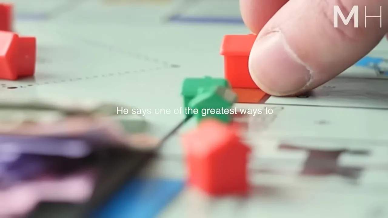 Finger placing a small red house on a board game, foreground and background pieces slightly out of focus