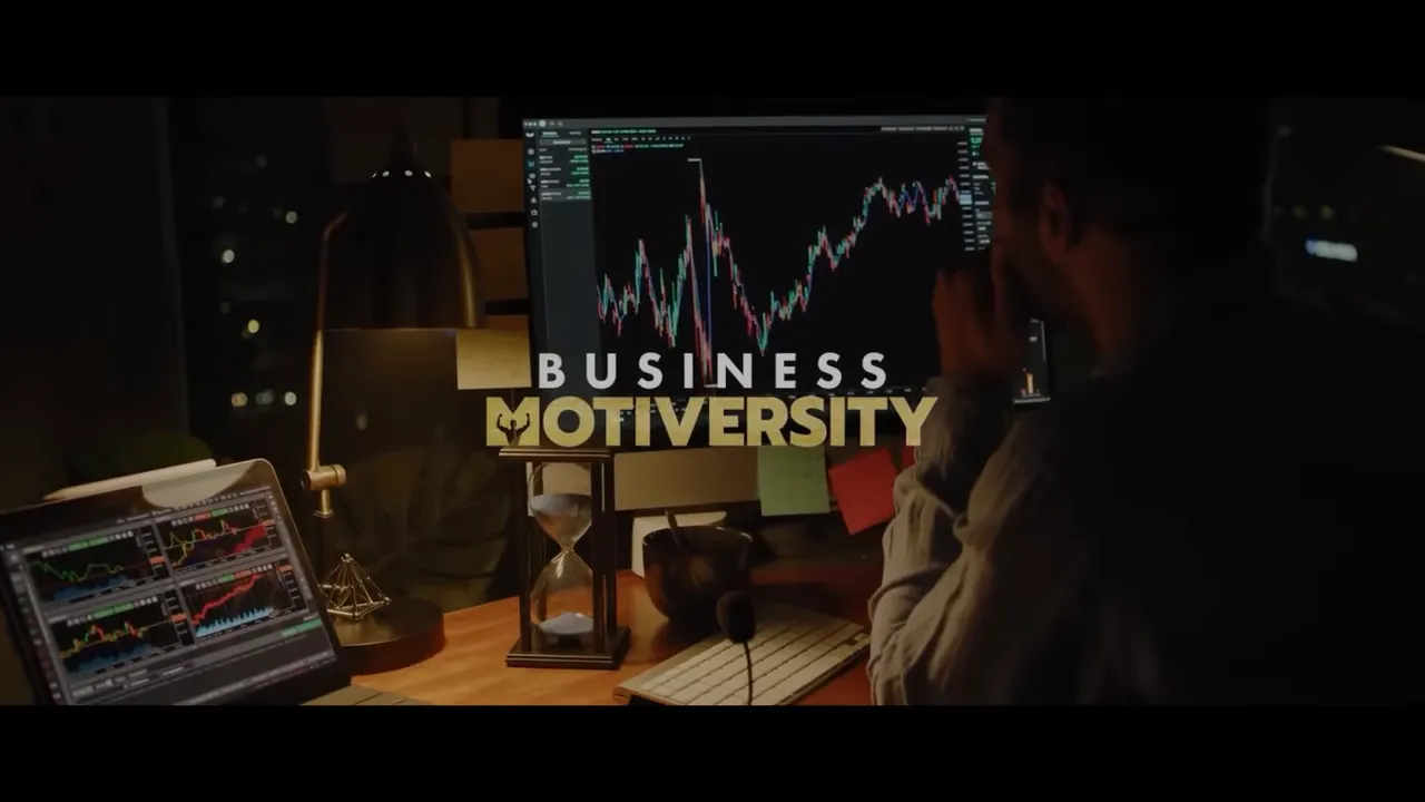 Workspace with a large monitor showing market-style line charts and a 'Business Motiversity' overlay, with an hourglass and laptop visible