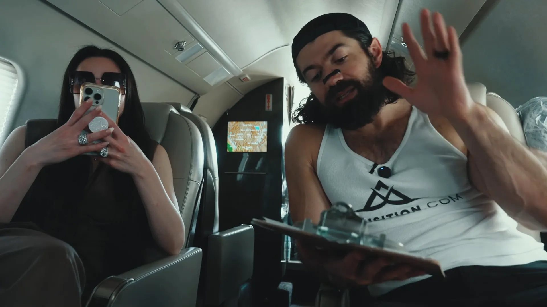 Alex holding clipboard with printed creative assets on a plane