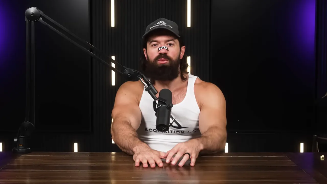 Host looking straight at camera behind a microphone, seated at a desk