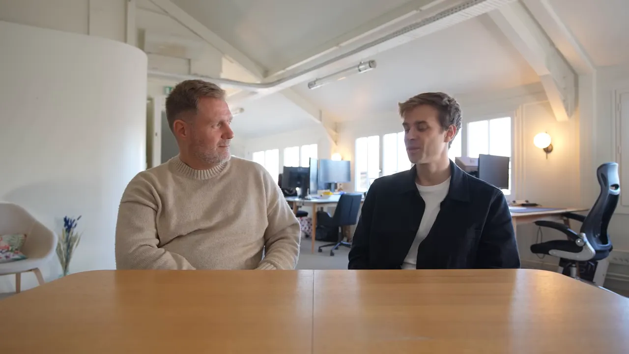 Two founders sit across a table in a bright office, discussing a prototype and MVP strategy.