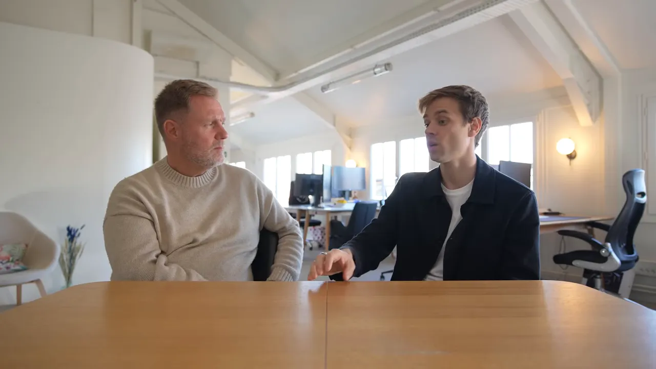 Two founders at a table in an office engaged in conversation about product and launch.