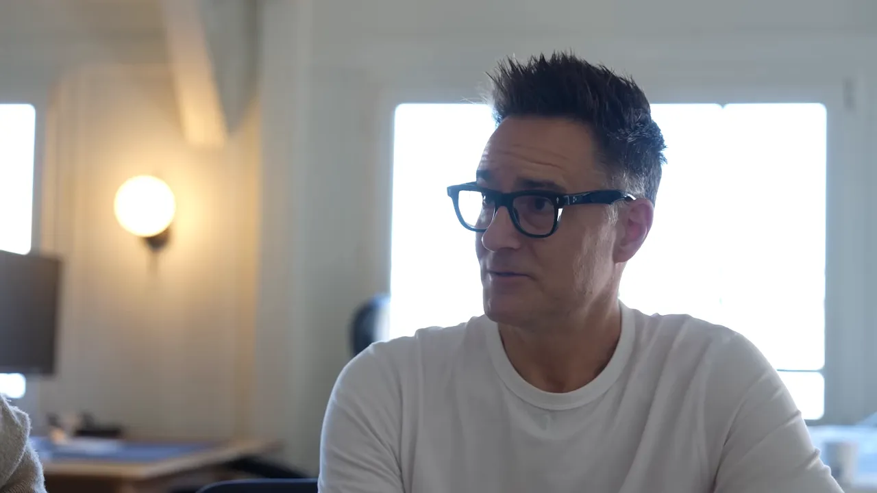 Person in a white shirt speaking during an office discussion about strategy and hiring