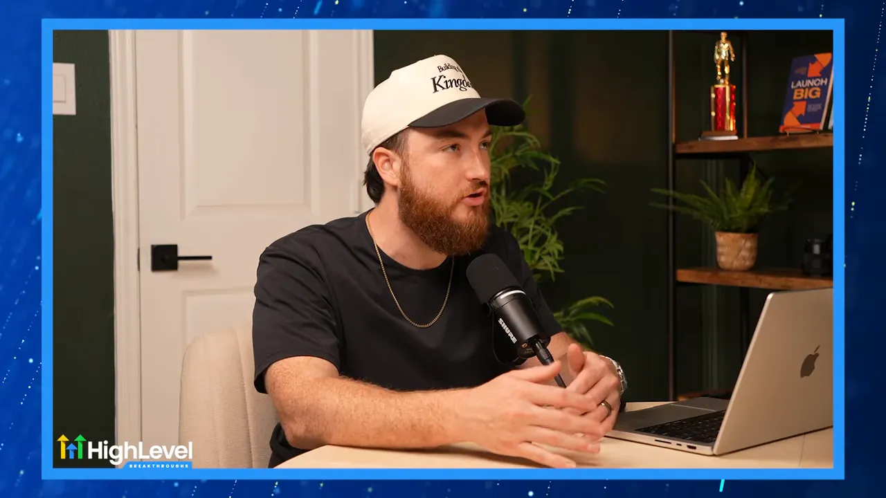 Podcast host gesturing while explaining a unified platform, microphone and laptop in view