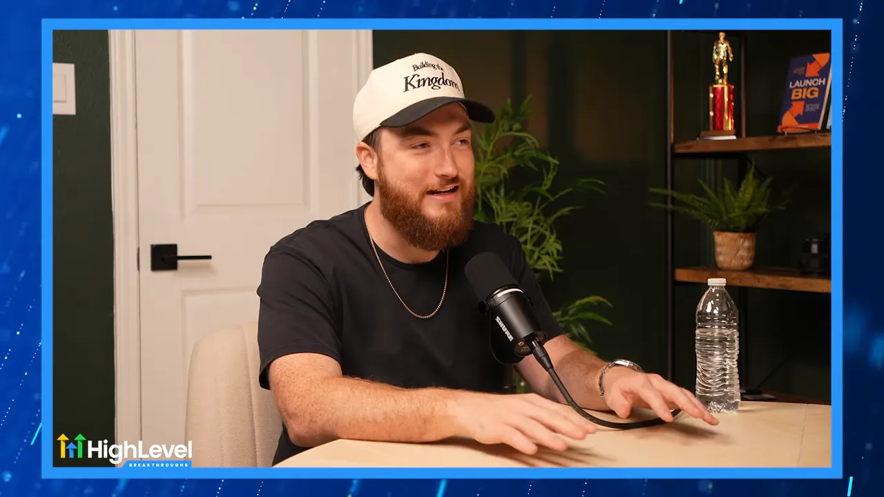 Smiling podcast guest speaking into a microphone with open hand gestures and background shelf