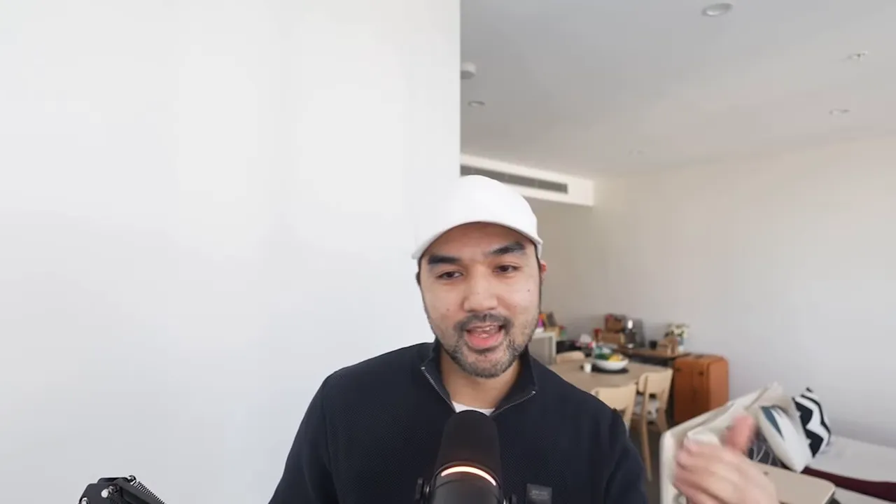 Person mid-gesture speaking into a microphone in a bright home office, conveying instructions about workflows.