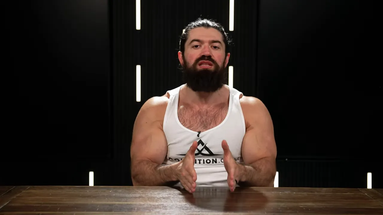 Person at a wooden table using both hands to frame a point while speaking, dark studio background