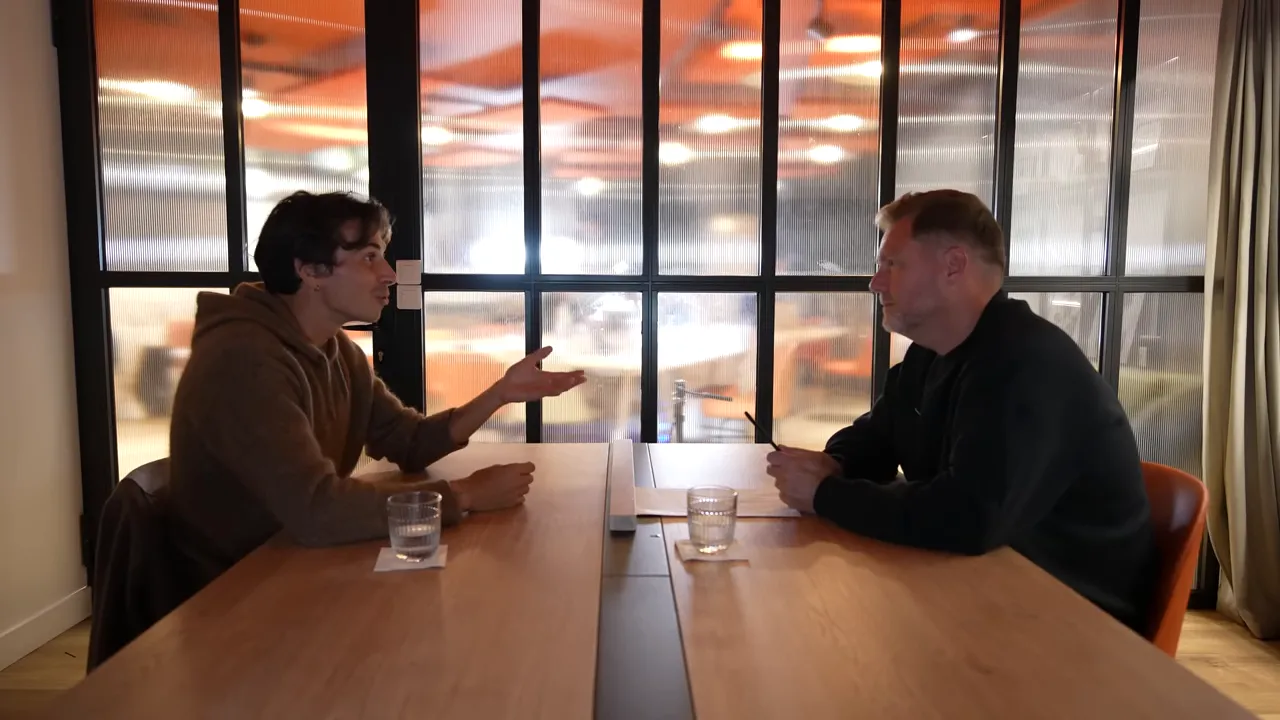 Two people conversing across a table with open hand gesture
