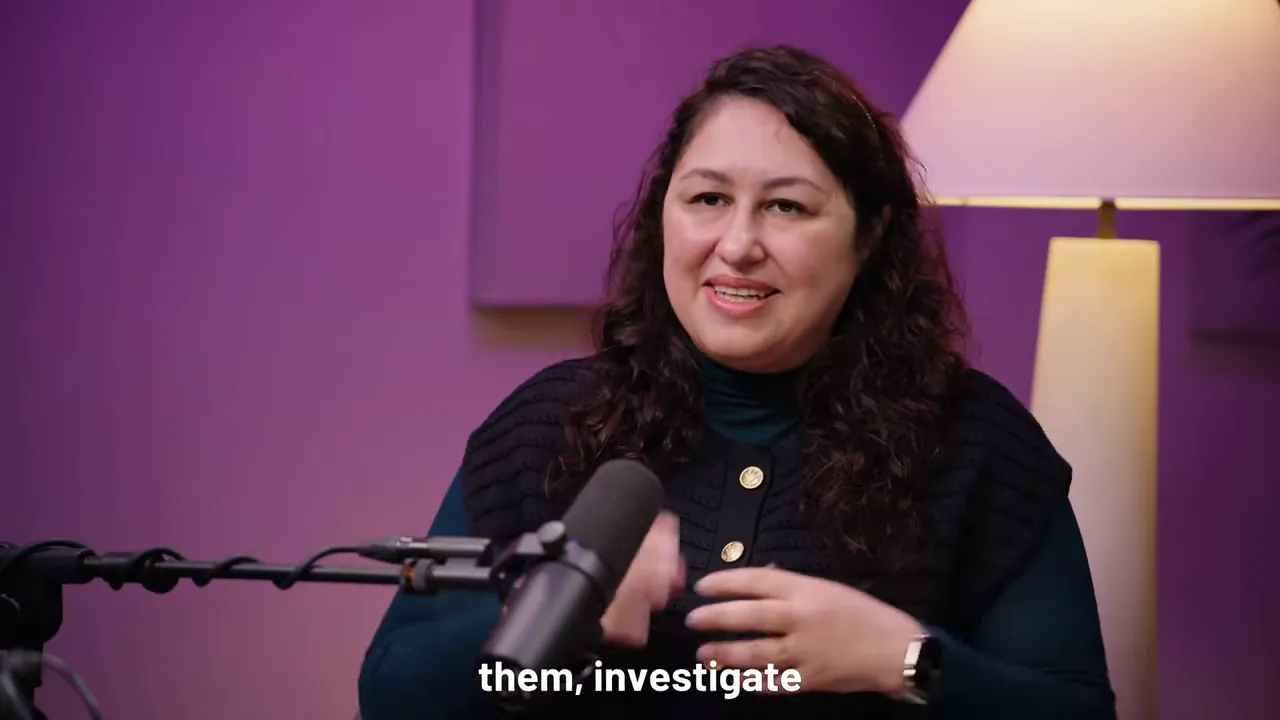 Podcast guest gesturing while explaining implementation, wide studio shot with microphone and lamp