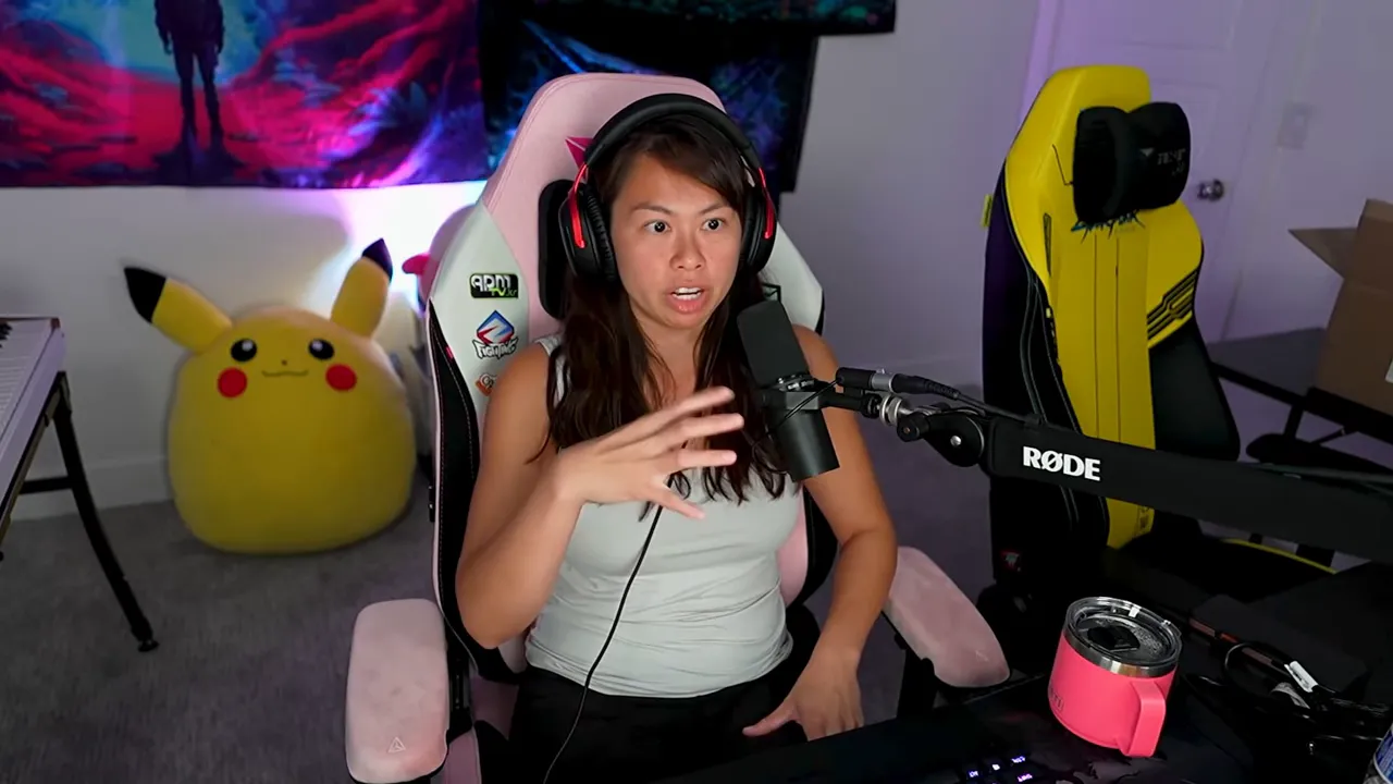 streamer gesturing with an open hand while speaking into a microphone, clear view of desk microphone and chair