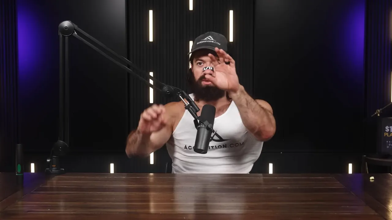 Podcast host reaching forward with both hands as if demonstrating or holding a small object, speaking into a boom microphone with studio lights behind.