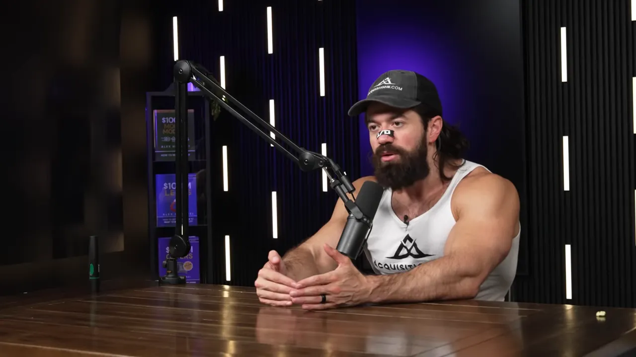 Podcast host leaning forward, gesturing with hands over a wooden table while speaking into a boom microphone in a dark studio with purple backlighting.