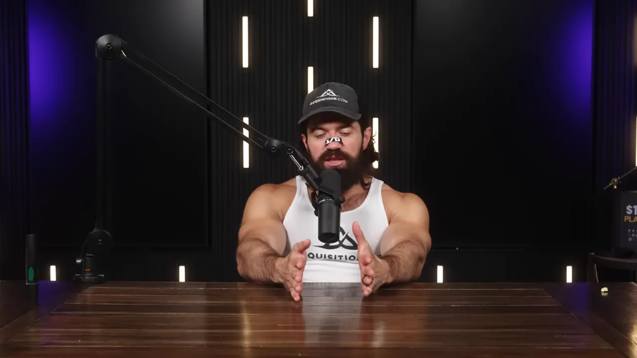 Podcast host centered at a wooden table, hands framing a space in front of the microphone with vertical lights and purple accents in the studio