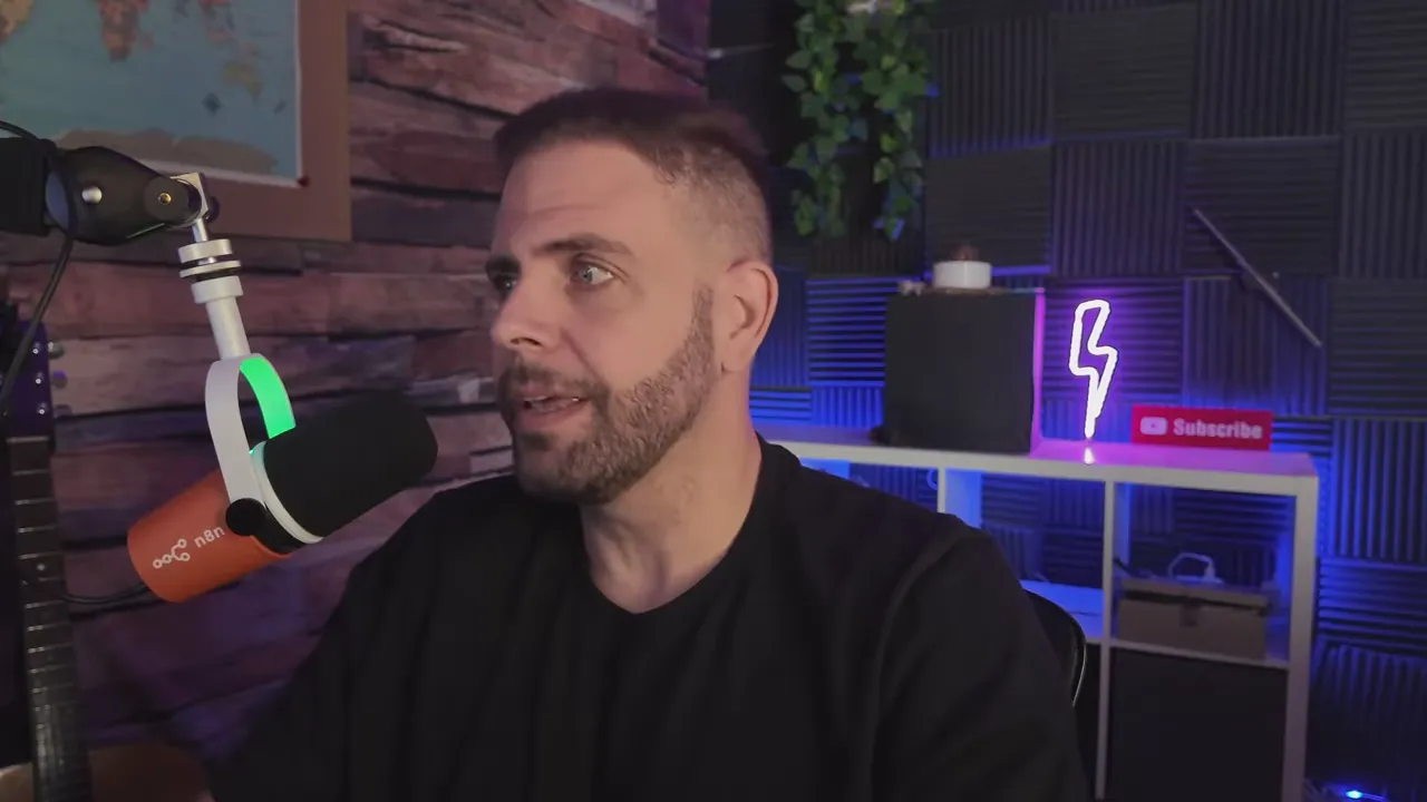 Host gesturing while speaking into a microphone with a laptop and studio background