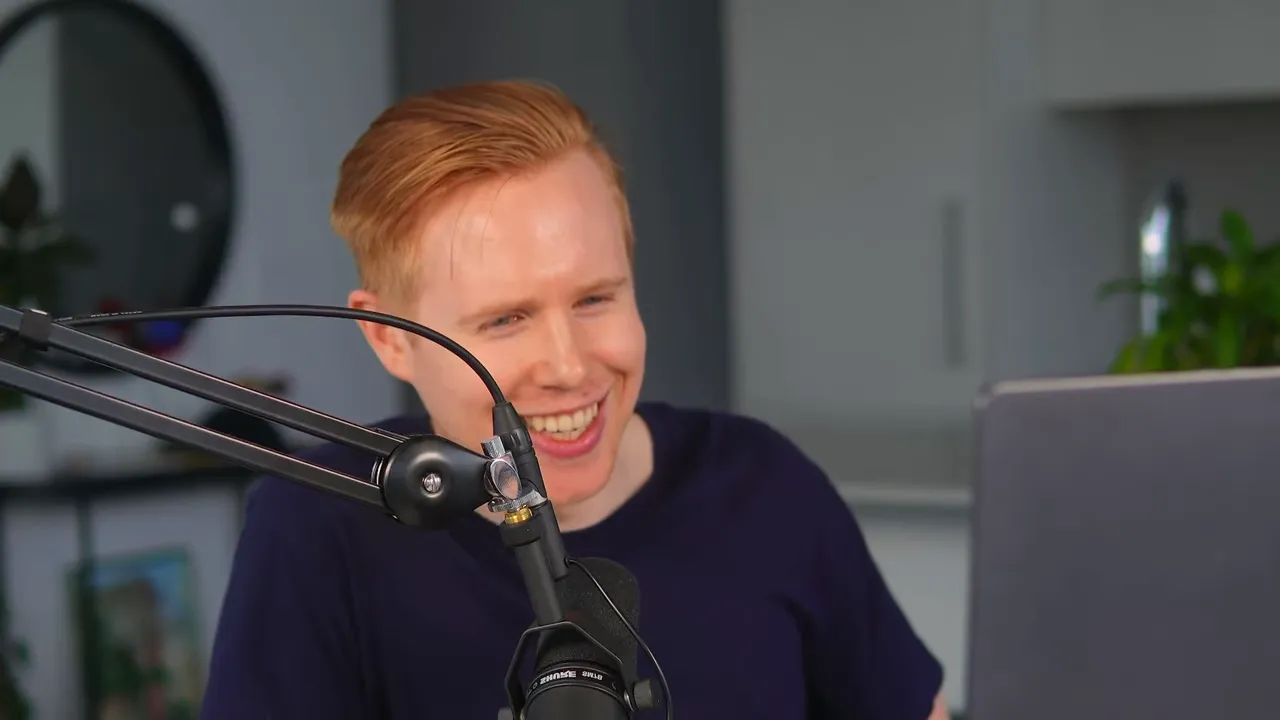 Presenter smiling while speaking into a boom microphone with laptop to the side