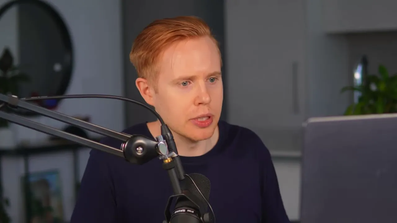 Presenter speaking into a studio microphone and looking at a laptop, clearly explaining a process