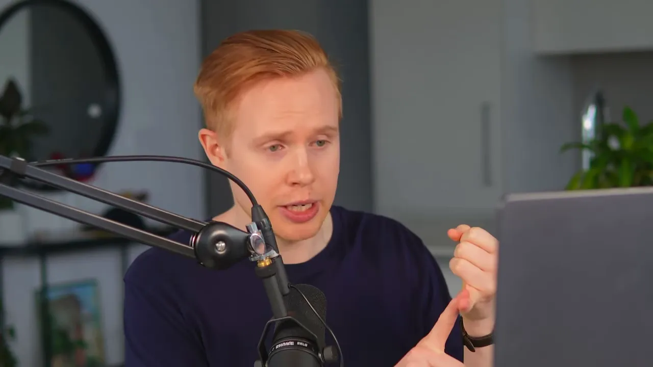 Presenter counting items on his fingers while speaking into a microphone and referencing a laptop