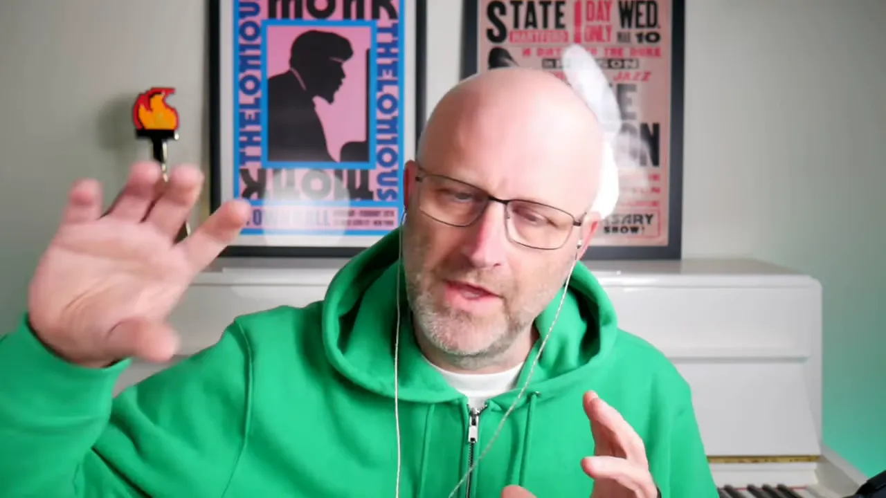 Presenter in green hoodie gesturing with hands while explaining integration concepts, posters and piano in background