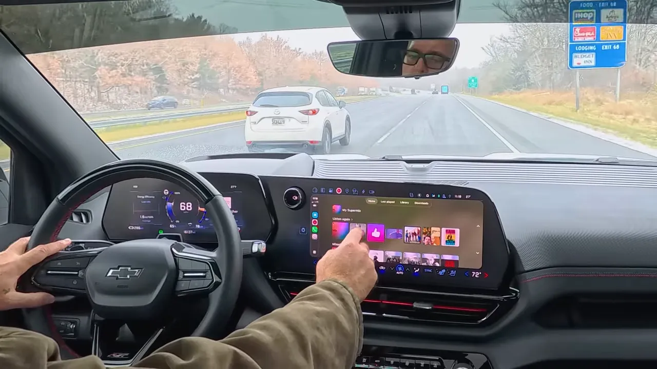 GM EV interior with finger interacting with the CarPlay music interface on the infotainment screen