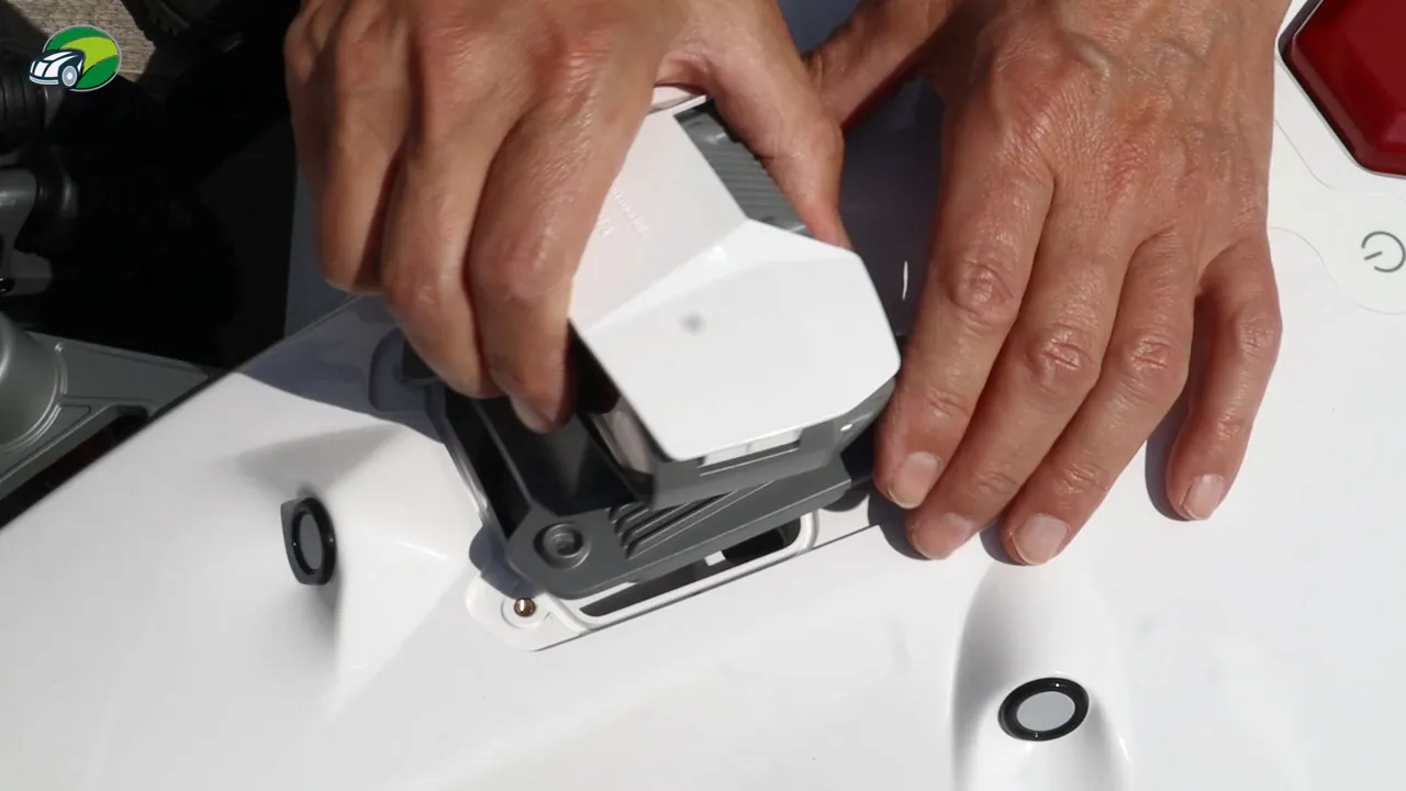 Close-up of hands installing the Luba 2 vision camera module into the mower's top cavity
