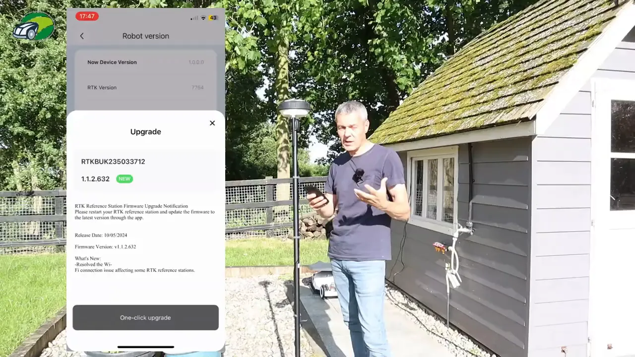 Mammotion app upgrade screen on a phone with the RTK reference pole and presenter gesturing next to the charging area.