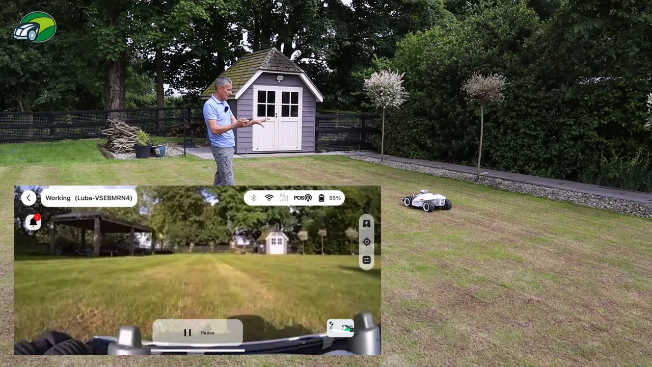 Mammotion Luba 2 on a lawn with the app's FPV video overlay showing the mower's forward camera view.