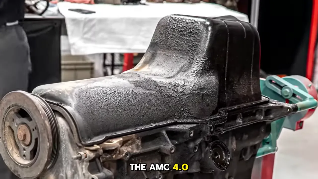 AMC 4.0 inline‑six engine long‑block on a stand showing the oil pan and front pulley with 'THE AMC 4.0' subtitle