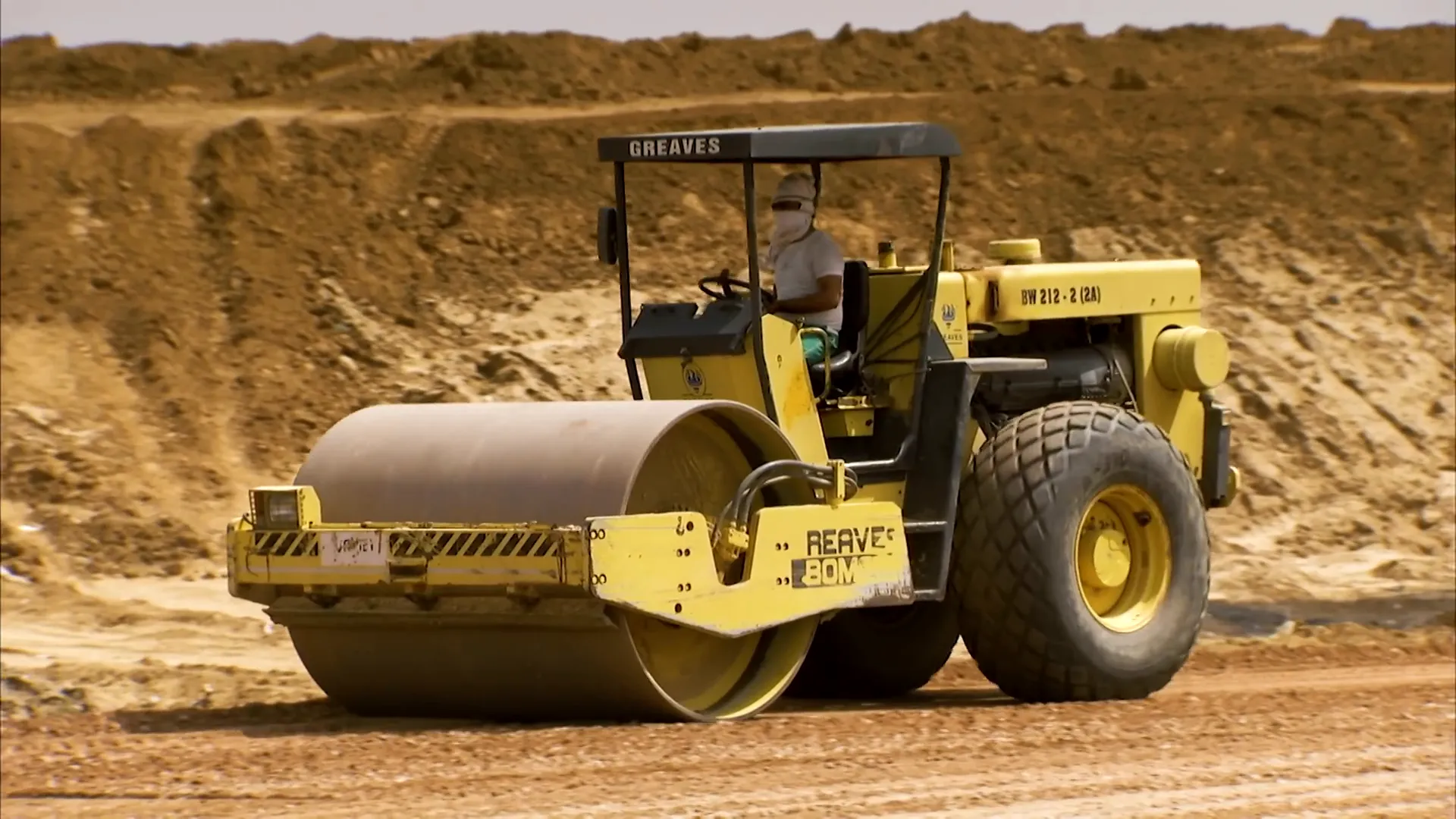 Roller compactor compacting soil on road