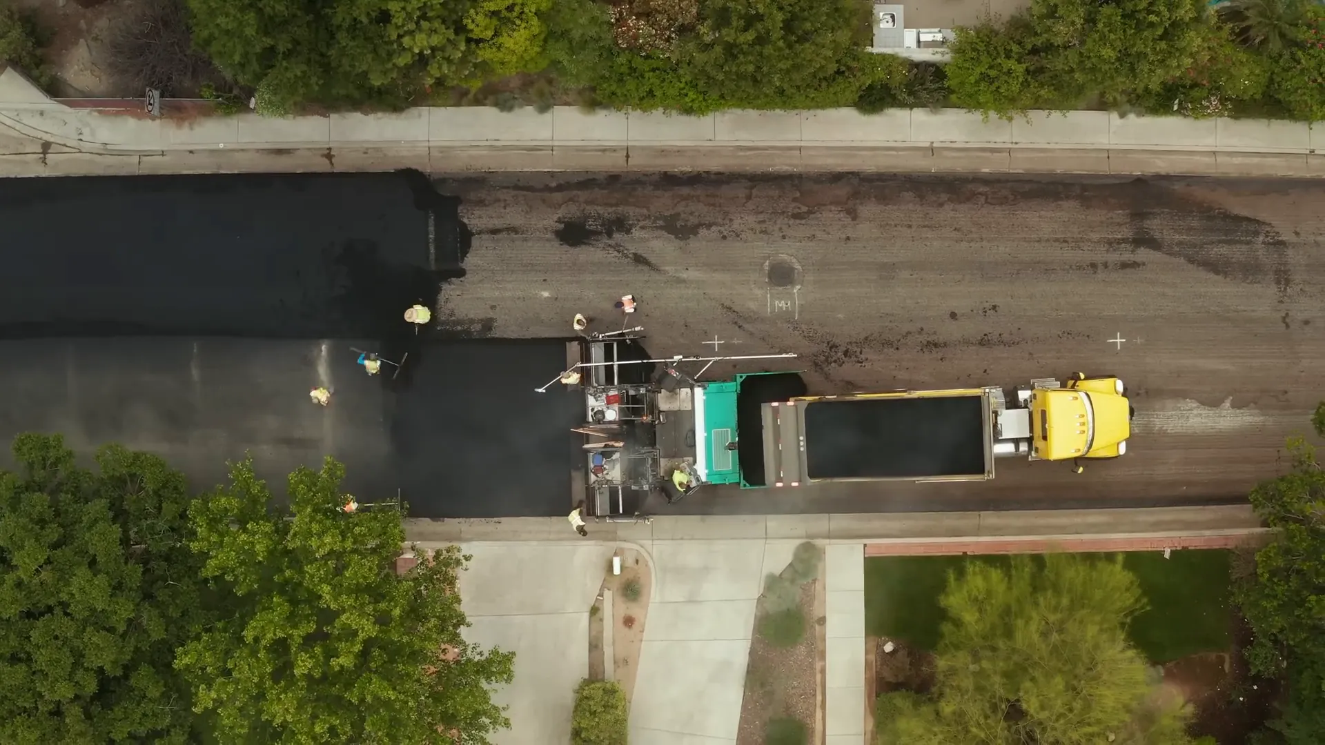 Paving train with dump truck, asphalt paver, and rollers