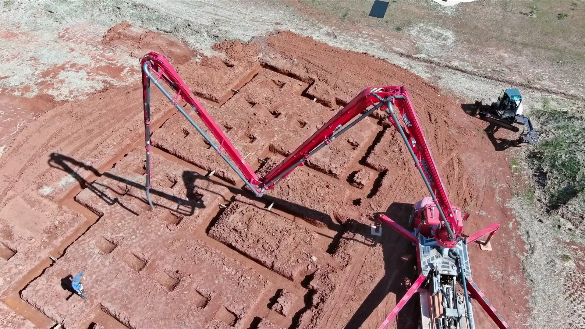 Concrete pump with overhead boom delivering concrete to site