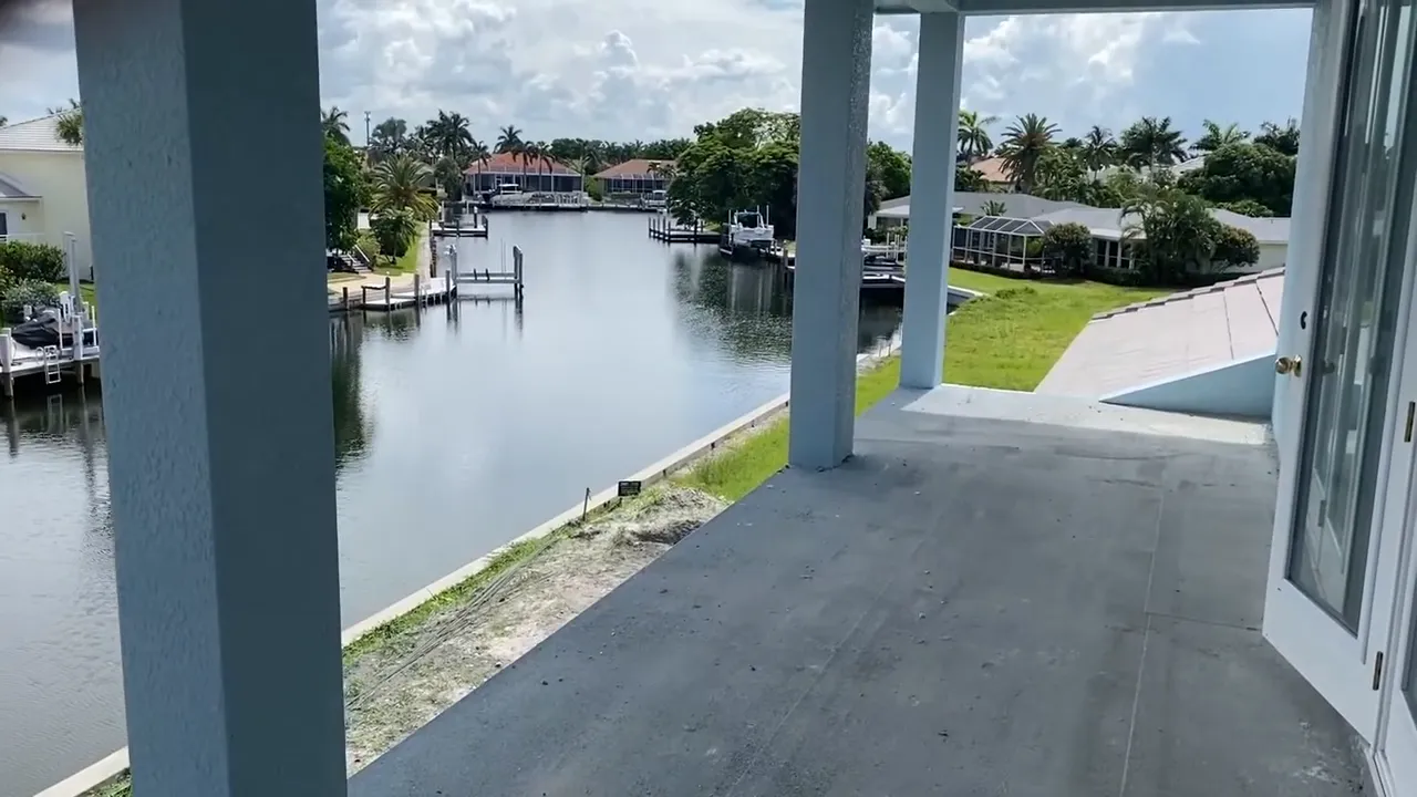 Covered patio overlooking a canal with docks and neighboring houses at a mid‑construction property