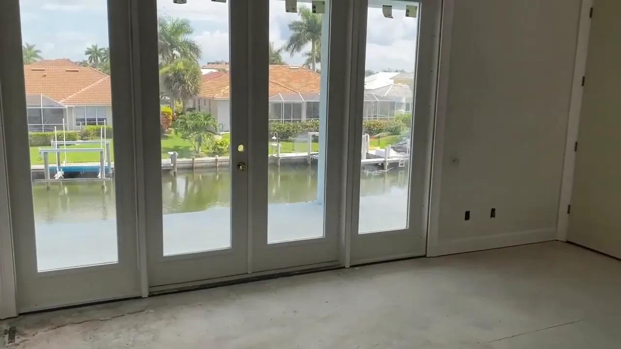 Interior view of floor-to-ceiling glass doors with canal view, unfinished flooring