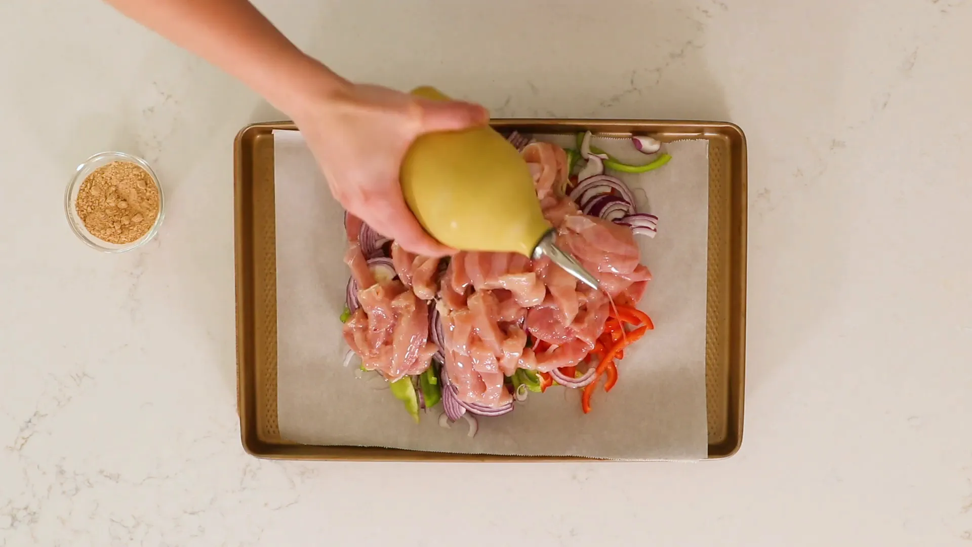 Fajita seasoning being sprinkled over the chicken and veggies.