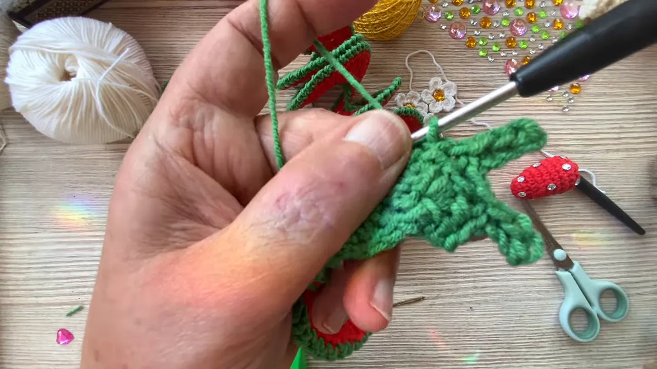 Close-up of a green crocheted cup with pointed leaf projections attached to a stem