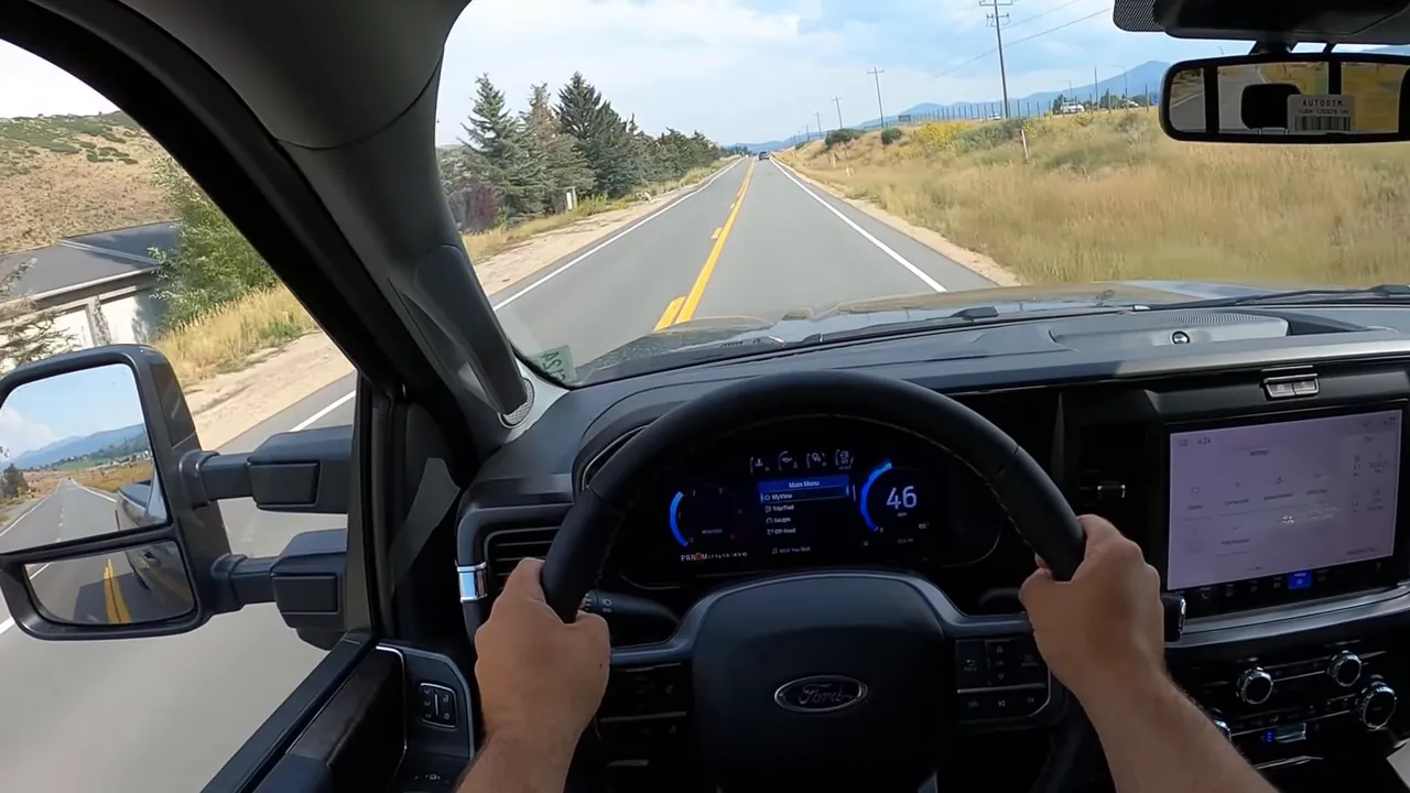 Front-facing driver view in 2026 Ford F-350 with both hands on the wheel, clear digital instrument cluster and straight road ahead