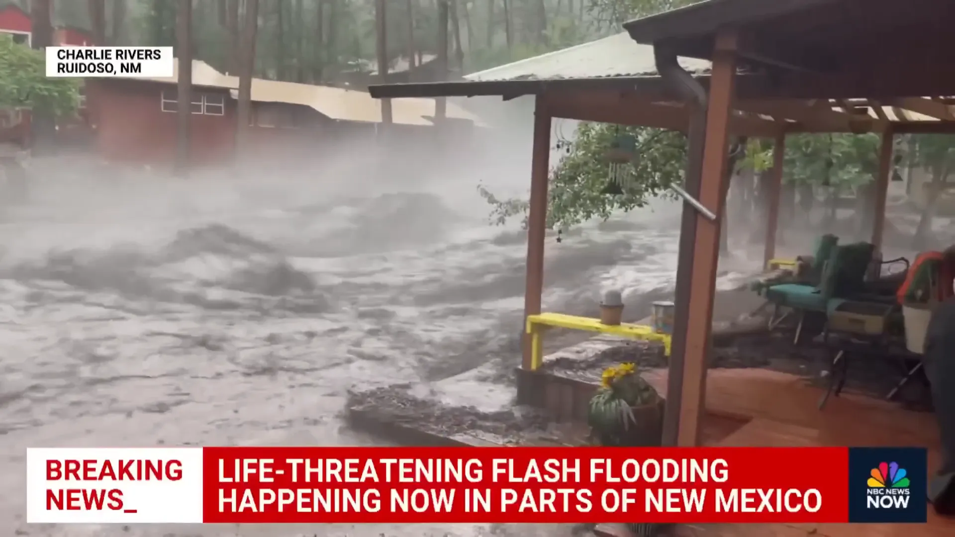 Floodwaters carrying debris and destroying a house near the mountains