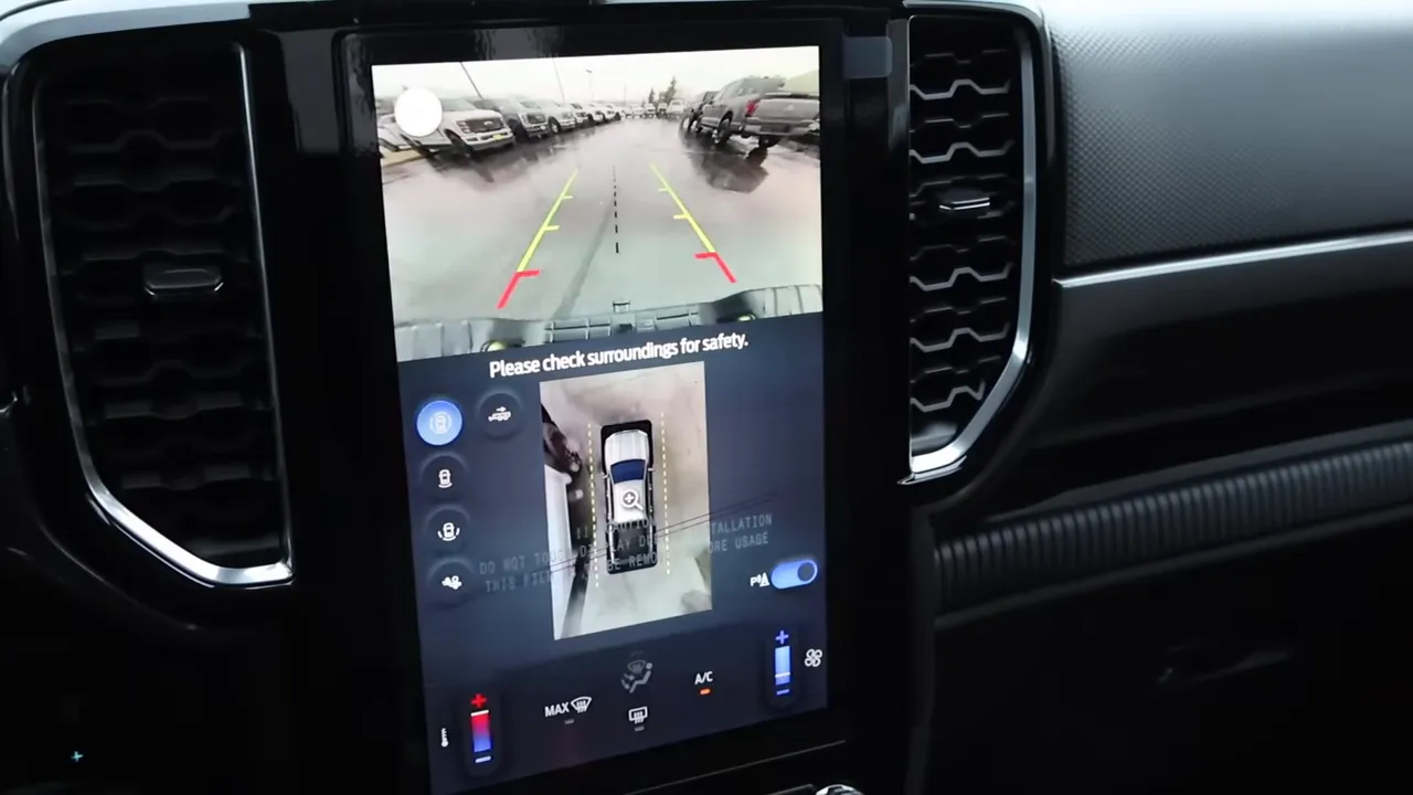 Vertical center touchscreen showing rear backup camera at top and 360-degree bird's-eye surround view below