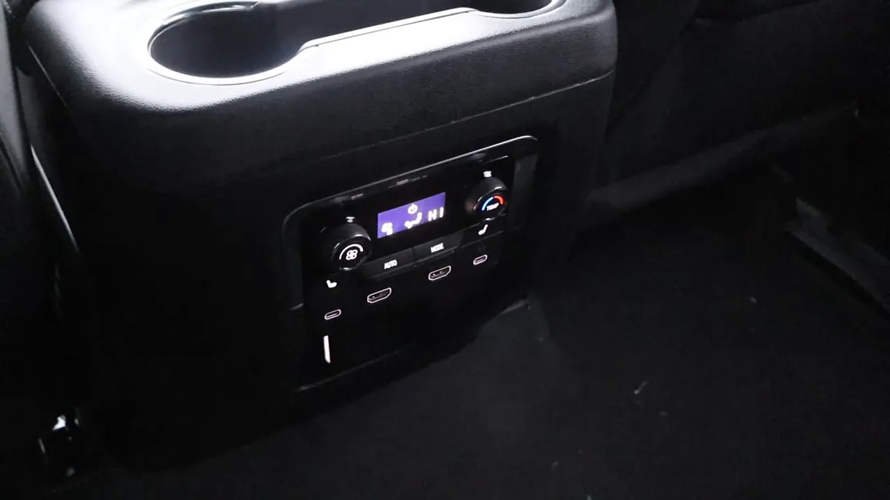 Second-row rear center console showing climate control knobs and multiple USB ports in an SUV