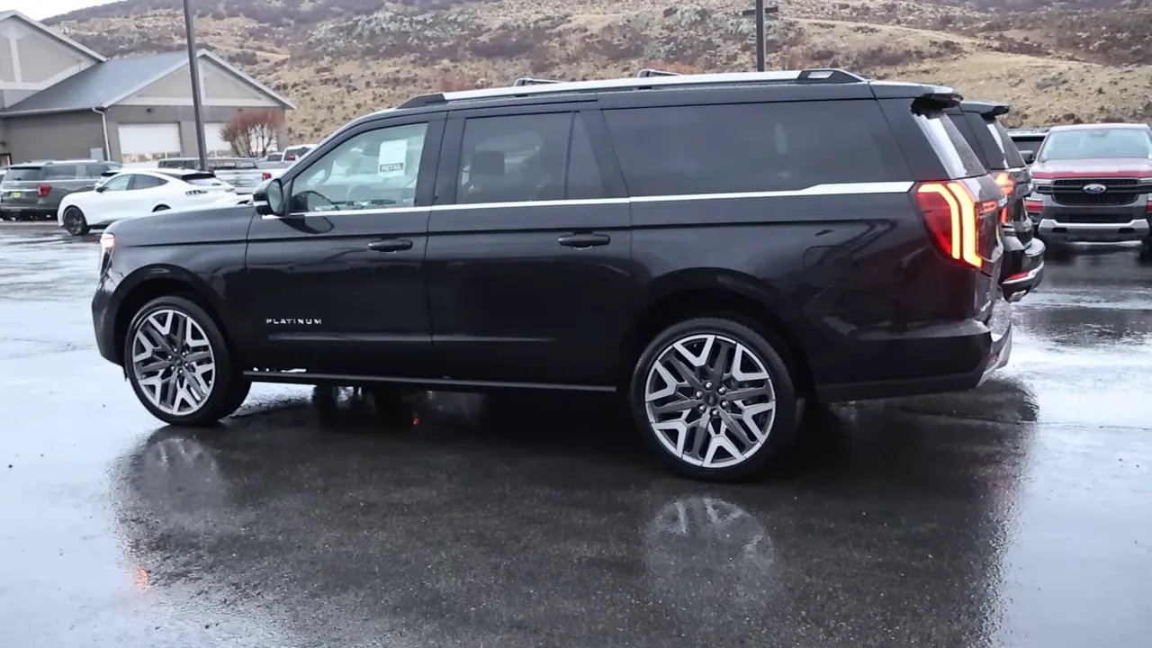 Full side view of a full-size SUV on wet pavement, showing wheels, roof rails and side badge.