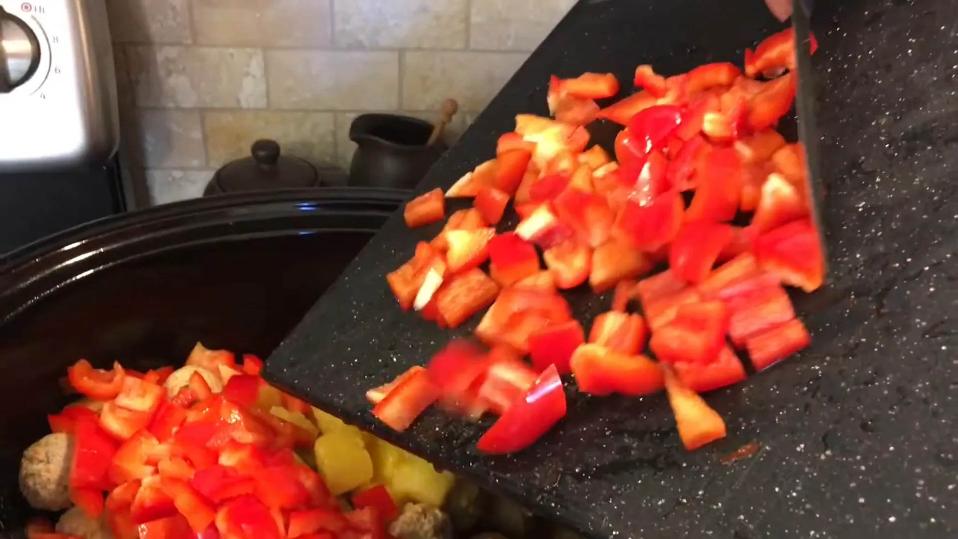 Adding diced bell peppers to the crockpot.